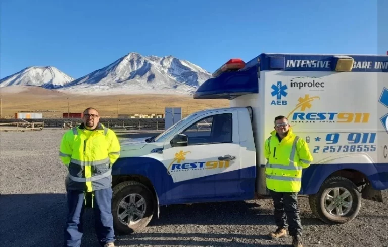 Ambulancia REST911 en faena de altura con personal paramédico y volcán nevado al fondo