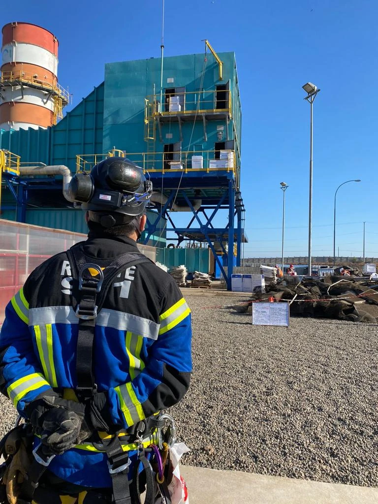 Rescatista REST911 con arnés frente a una estructura industrial en construcción