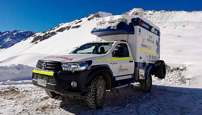 Camión de rescate en nieve en zona montañosa con equipo especializado y logotipos de emergencia.